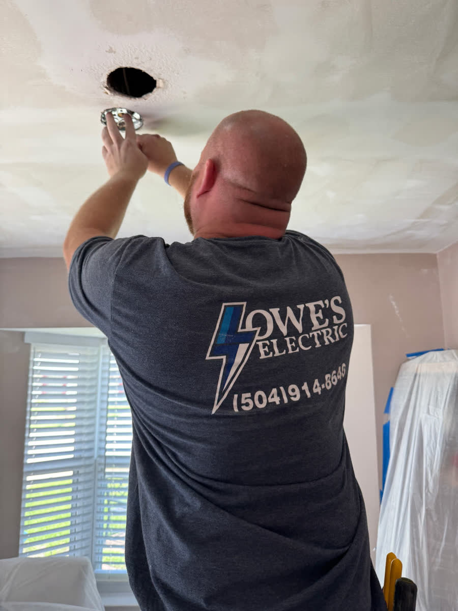 A Lowe’s Electric electrician installing a ceiling light fixture